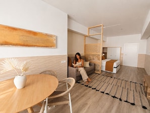 A modern hotel room with a sofa, a dining table with chairs, a decorative rug, and a bed with a wooden headboard. - Valencia Urban Suite VI | 4 Guests | A/C & Wi-Fi | Near the City Center (Valencia)