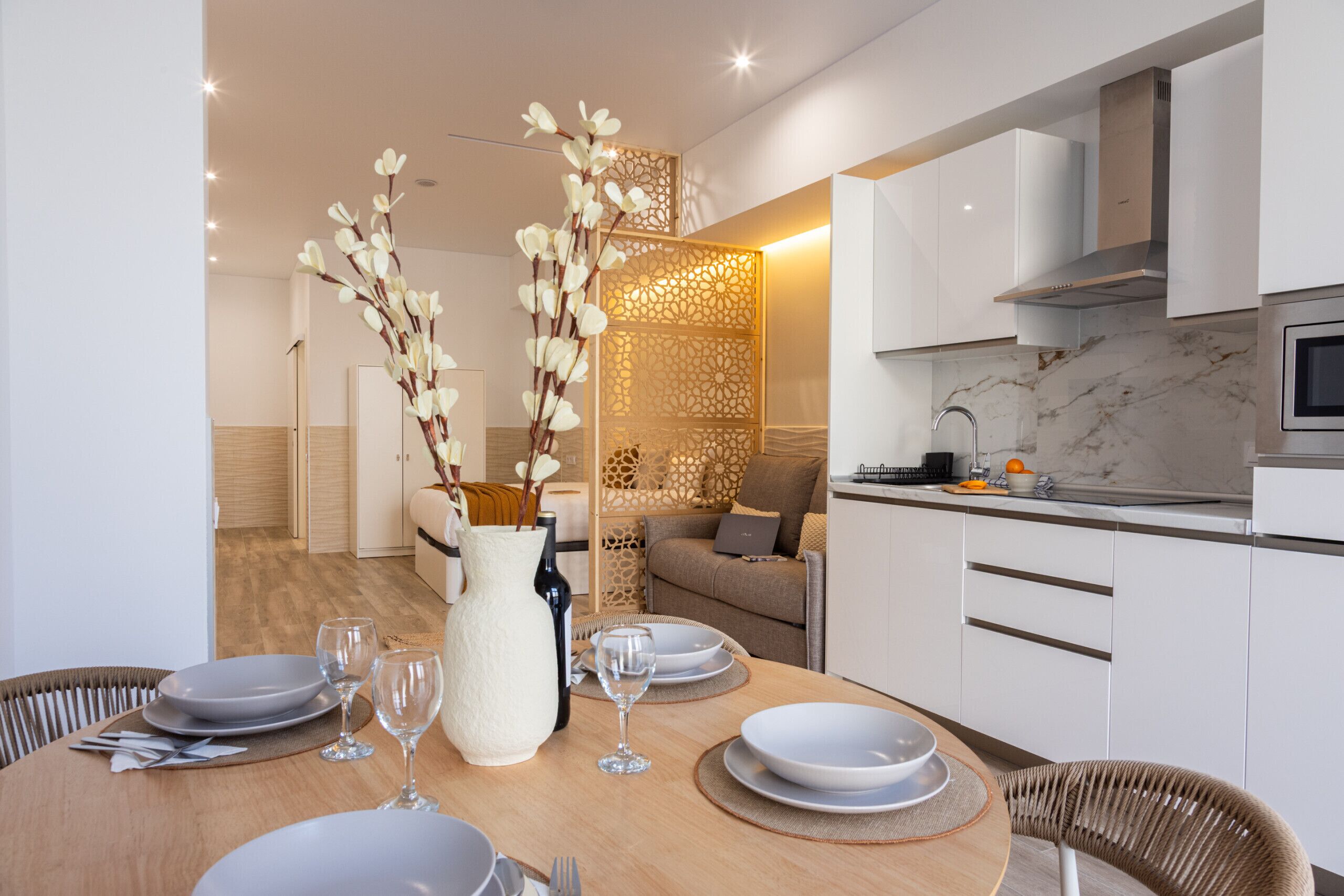 A modern kitchen with white cabinets, a marble countertop, and a built-in oven.