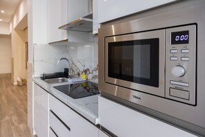 Een moderne keuken met een roestvrijstalen magnetron, een digitale klok en een spoelbak met afwassysteem.