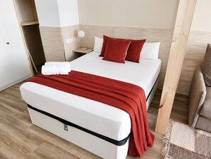 Ein Hotelzimmer mit einem Bett, einem Nachttisch, einer Lampe und Holzboden.