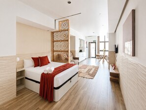 Ein modernes Hotelzimmer mit einem Bett, einer Holzwand, einem Essbereich und einem an der Wand befestigten Fernseher.
