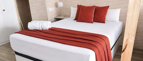 Une chambre d’hôtel avec un lit, une table de chevet, une lampe et un plancher en bois.