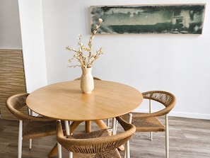 A round wooden table with a vase of branches, surrounded by wicker chairs. - Valencia Urban Suite IX | 4 Guests | A/C & Wi-Fi | Near the City Center (Valencia)