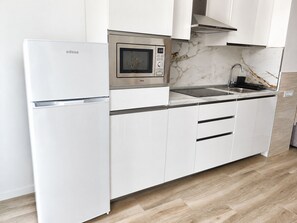 A modern kitchen with white cabinetry, a built-in microwave, and a stainless steel sink. - Valencia Urban Suite IX | 4 Guests | A/C & Wi-Fi | Near the City Center (Valencia)