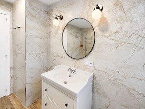 A bathroom with a marble wall, a round mirror, a white sink, and two wall-mounted lights. - Valencia Urban Suite IX | 4 Guests | A/C & Wi-Fi | Near the City Center (Valencia)