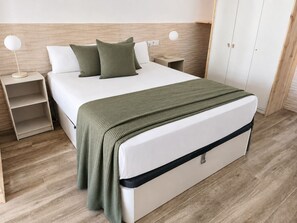 A neatly made bed with a white headboard, two pillows, and a green blanket. There are two bedside tables with lamps, and a wardrobe is visible in the background. - Valencia Urban Suite IX | 4 Guests | A/C & Wi-Fi | Near the City Center (Valencia)