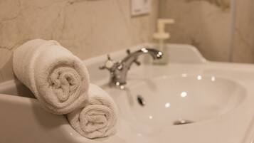 A bathroom sink with two rolled towels placed on it.