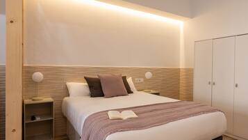 A neatly arranged bedroom with a bed, bedside tables, and a wardrobe.