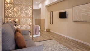 Een moderne woonkamer met een bank, decoratieve wandpaneel, flatscreen-tv en kunstwerk.