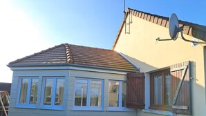 A small, single-story house with a gabled roof and a covered porch. - Charming house in a quiet location, in the center of town, less than 800 m from the beach and all amenities (Cabourg)