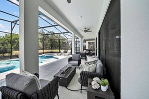 Uma área externa coberta com piscina, assentos e uma televisão.