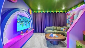 Una habitación colorida con una televisión, un sofá, una mesa de centro y una cortina.