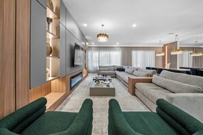 A modern living room with a sectional sofa, a coffee table, and a TV mounted on the wall. - 10BR house with pool table near Disney area (Orlando)