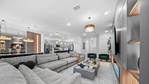 Una sala moderna con un amplio sofá modular, una mesa de centro y un televisor.
