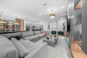 Ein modernes Wohnzimmer mit einem großen Ecksofa, einem Couchtisch und einem Fernseher.