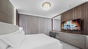 Una habitación de hotel moderna con una cama grande, un televisor montado en una pared de paneles de madera y un espejo grande sobre el tocador.