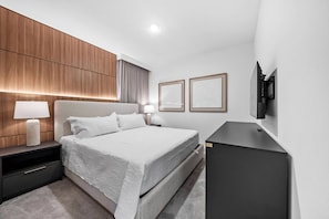A modern hotel room with a bed, bedside tables, a TV, and framed artwork on the wall. - 10BR house with private pool in Paradiso Grande (Orlando)