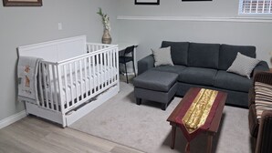 Un salon avec un berceau blanc, un canapé gris et une table basse en bois.