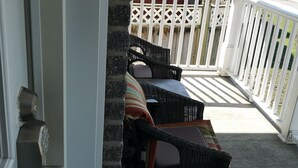 Un balcon doté de meubles en osier et offrant une vue sur un bâtiment en briques.