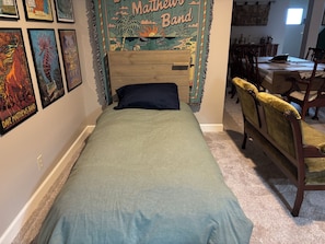 Une chambre avec un lit, une chaise et un mur décoré de posters de groupes de musique.