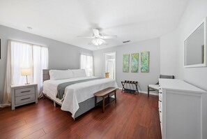Ein Schlafzimmer mit Bett, Nachttisch, Bank, Kommode und Bildern an der Wand.