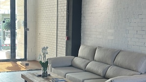 A modern living room with a grey sofa, a wooden coffee table, and a brick wall. - Tudcon Palm (Madrid)