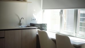 A compact kitchen with a sink, a stove, and a window with blinds. - Tudcon Palm (Madrid)