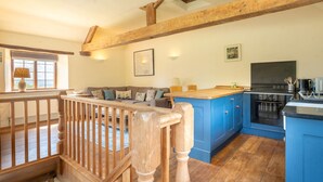 Un vaste espace de vie agrémenté d’un escalier en bois, une cuisine avec des meubles bleus et un coin repas comprenant une table et des chaises.