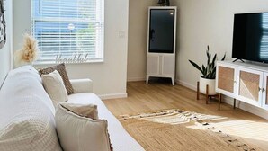 A modern living room with a white sofa, a flat-screen TV, and a decorative ceiling light. - Cozy Multi-level Townhome South Tampa 2BD2BA (Tampa)
