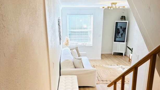 A staircase leading to a living room with a white sofa, a bench, and a framed picture on the wall. - Cozy Multi-level Townhome South Tampa 2BD2BA (Tampa)