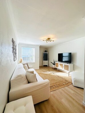 A modern living room with a sofa, TV, and a decorative wall piece.