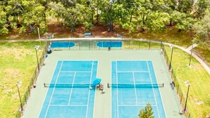 A tennis court with two courts, surrounded by a fence, trees, and a bench. - Cozy Multi-level Townhome South Tampa 2BD2BA (Tampa)