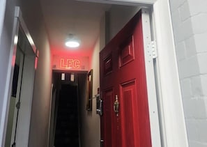 Un pasillo con una puerta roja y un letrero de neón que dice 'LFC'.