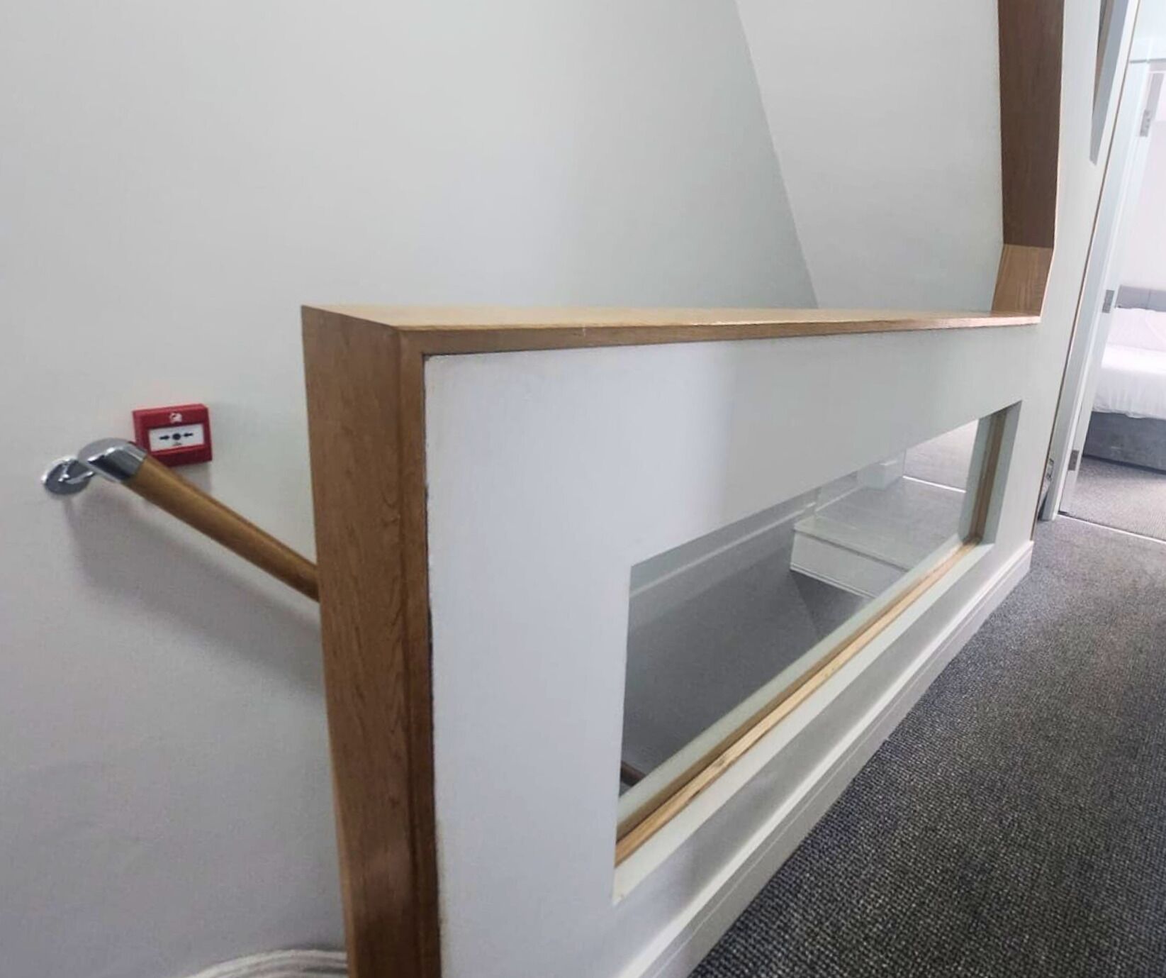 Un intérieur moderne avec une fenêtre à cadre en bois et une rampe d’escalier en métal.