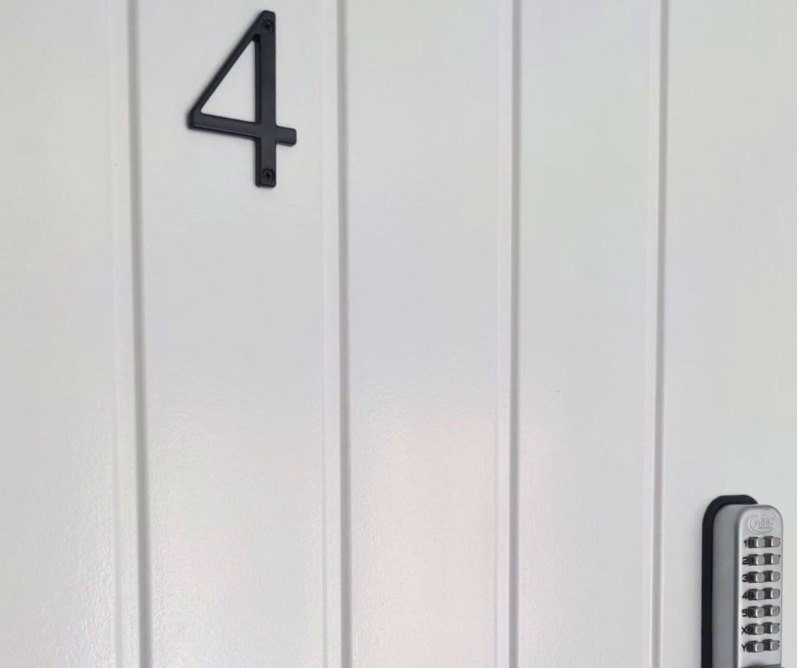 En vit vägg med en svart siffra ’4’ på och en fjärrkontroll fäst på den.