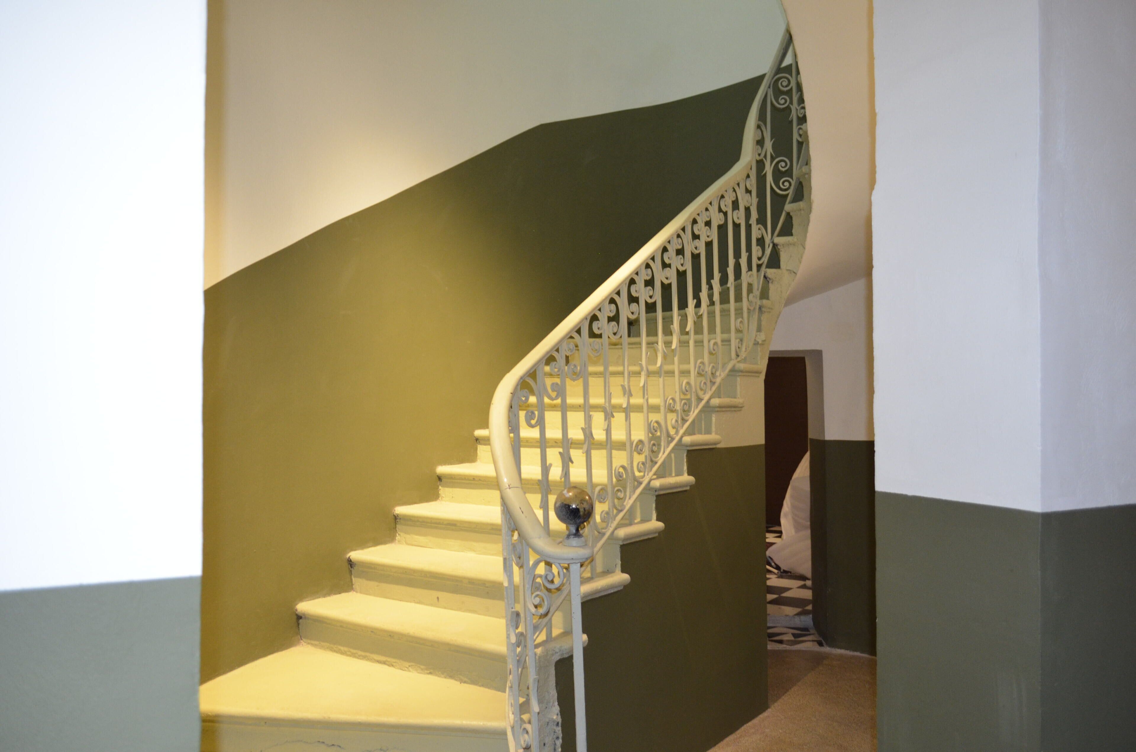Eine Treppe mit aufwendiger weißer Geländer und einer grünen Wand.