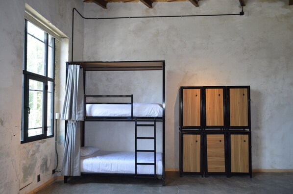 A bunk bed with a ladder, a wooden wardrobe, and a window with curtains. - Nomaddicts (Mexico City)