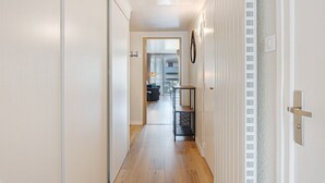 A hallway with a wooden floor, a black metal shelf, and a white door with a handle. - Apartment 'Les Gemaux 2' in Villard-de-Lans, 6 Guests, 1 Main Bedroom and Cabin Room (Villard-de-Lans)