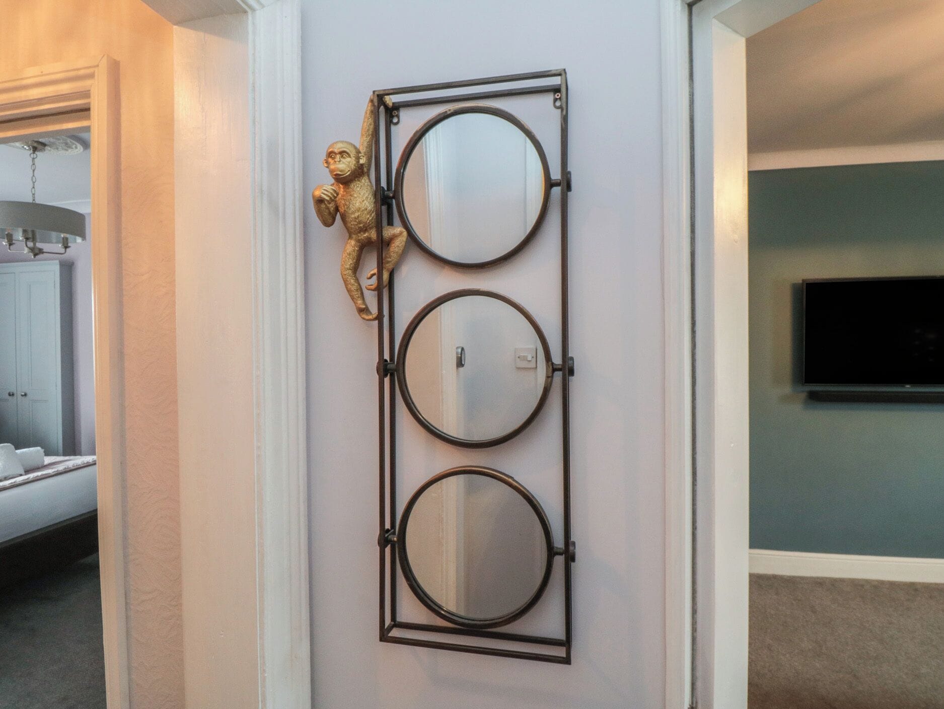 A wall-mounted mirror with three circular mirrors and a monkey figurine.