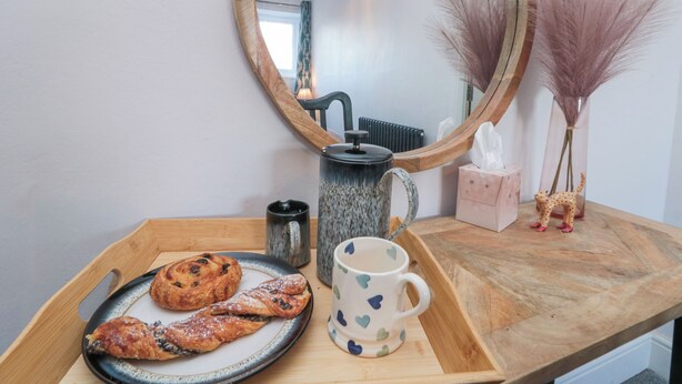 A wooden tray with pastries, a mug, and a teapot on a kitchen counter. - Cuckoo's Nest (Whitby)