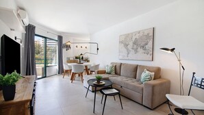 Een moderne woonkamer met een bank, salontafel en een eethoek met stoelen en een tafel.