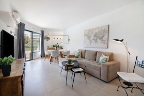 Een moderne woonkamer met een bank, salontafel en een eethoek met stoelen en een tafel.