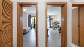 Een gang met houten deuren die leiden naar een slaapkamer en een eetruimte met uitzicht.