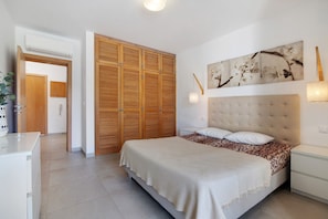 Een slaapkamer met een bed, nachtkastjes, een kledingkast en een kunstwerk aan de muur.