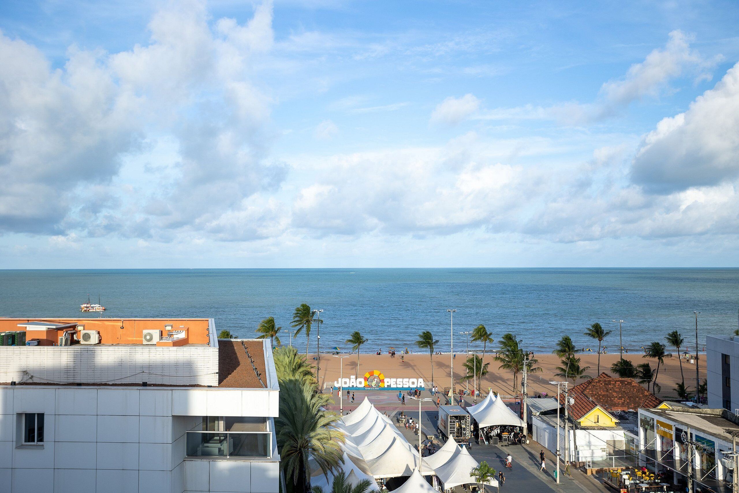A beachside view with a clear sky, palm trees, and a beach.