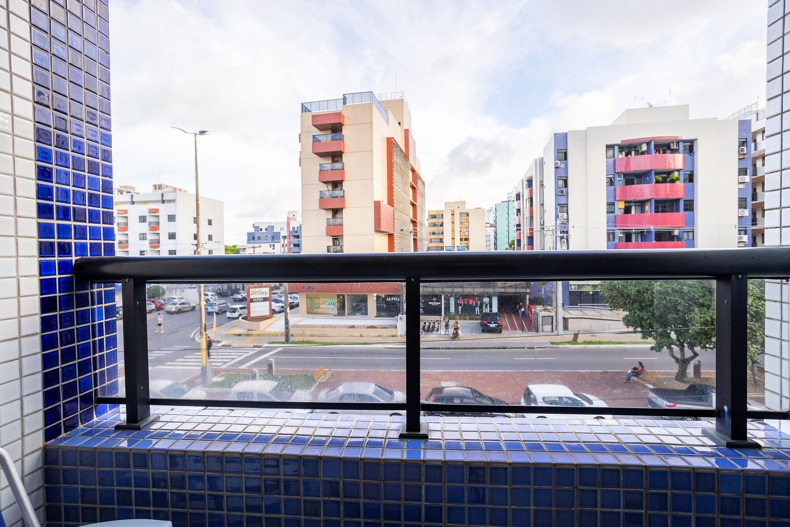 A view from a window with blue-tiled walls, overlooking a street with cars and buildings.