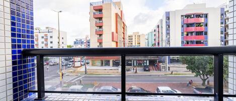 A view from a window with blue-tiled walls, overlooking a street with cars and buildings.