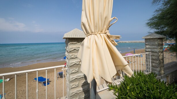 Une vue sur la plage avec un mur de pierres, un parasol et une chaise.