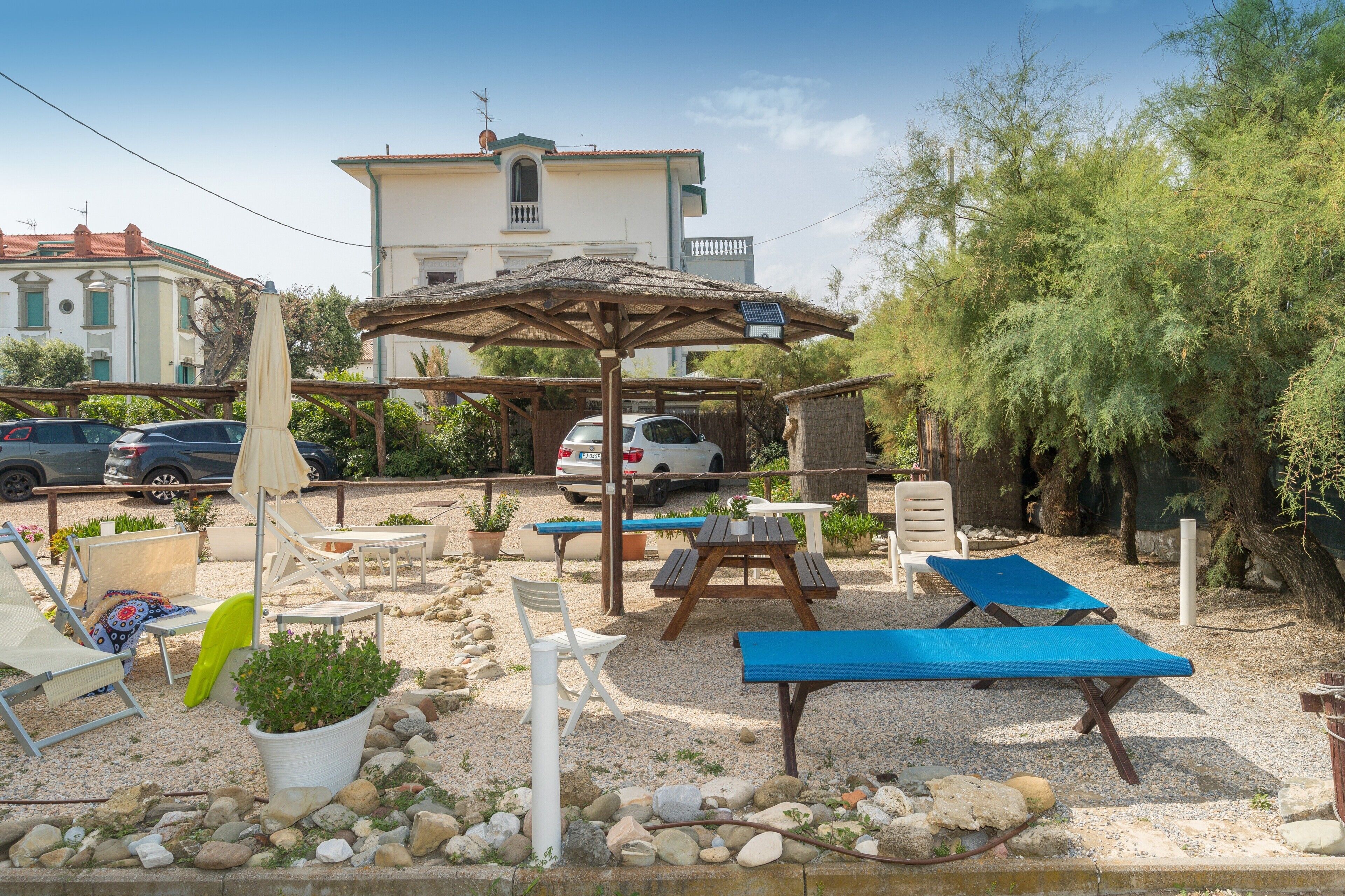 An outdoor seating area with lounge chairs, a table, and a pergola with a solar panel.