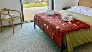 Een hotelkamer met een bed, een stoel en uitzicht op zee.